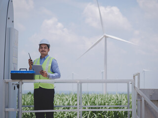Engineer man is using a tablet to control and monitor the operation of a wind turbine in the...