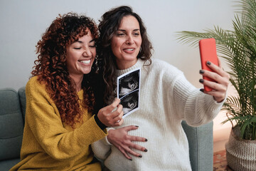 Happy gay lesbian couple holding ultrasound photo scan on video call - Growing baby in pregnancy time concept - obrazy, fototapety, plakaty