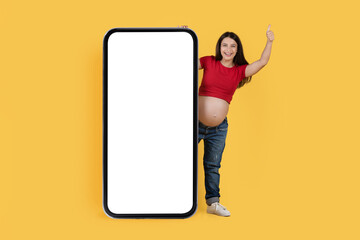 Nice Promo. Positive Pregnant Woman Peeking Out Behind Big Blank Smartphone