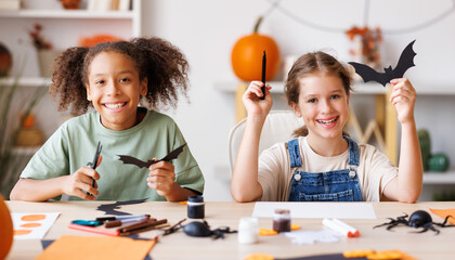 Happy multinational children girls making Halloween home decorations together