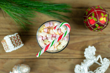 hot chocolate drink with marshmellows and candy cane on wooden christmas background. selected focus