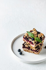 Baked oatmeal squares with fresh blueberry and mint leave on white background with text space. Menu, recipe