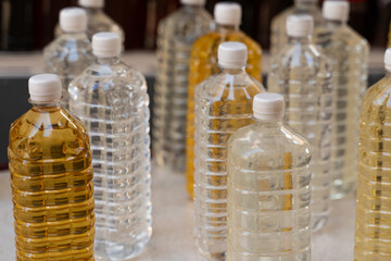 Close-up of many plastic bottles with clear and yellow liquid. Homemade alcohol bottled in plastic containers.
