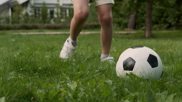 Legs of a child who plays with a soccer ball.