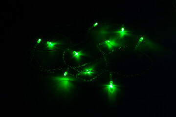 Fototapeta na wymiar Christmas garland with green lights on black background, selective focus