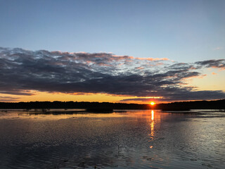 View of the sunset on the lake between the reeds, with blue skies and clouds. Tourism and travel concept.