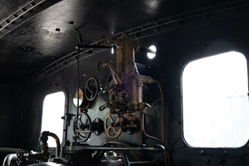 Black pressure gauge of an old steam engine in the train engine room with pipelines
