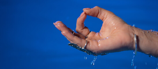 Hand of woman in mudra om in water, pool or river. Meditating in summer. Clean water . Girl calms...