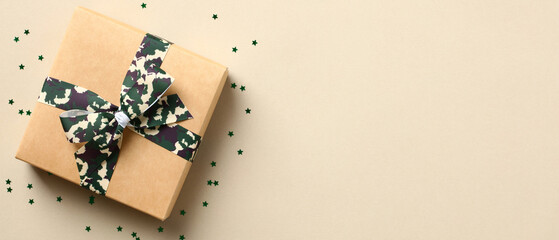 Gift box with camouflage military ribbon bow and confetti on beige background. USA Veterans Day...
