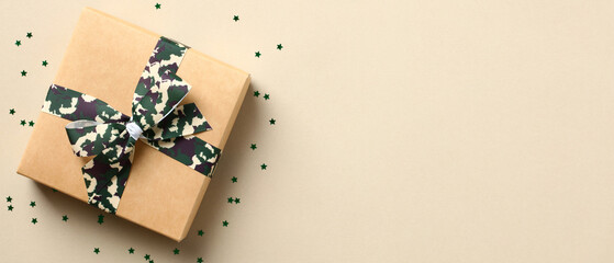 Gift box with camouflage military ribbon bow and confetti on beige background. USA Veterans Day banner design.