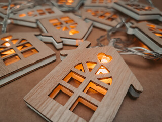 Garland with wooden houses and gold warm light laying on brown background