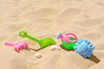Fototapeta na wymiar Bright plastic rake and shovel on sand. Beach toys. Space for text