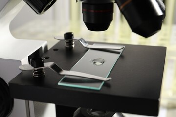 Microscope with drop of urine on glass slide in laboratory, closeup