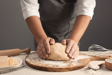 Man kneading dough at table near grey wall, closeup