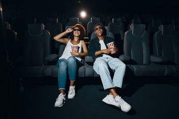 Couple watching movie with popcorn in cinema.