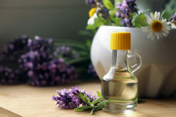 Obraz na płótnie Canvas Bottle of natural lavender essential oil near mortar with flowers on wooden table, closeup. Space for text