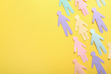 Many different paper human figures on yellow background, flat lay with space for text. Diversity...