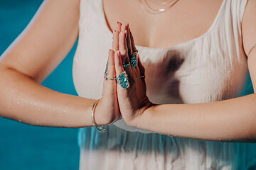 Woman holding namaste in clean water. Palms with gypsy boho rings. Meditation, praying, gratitude, purity background. 