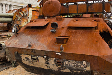 A destroyed rusty military vehicle stands outdoors on the street. Wreck. Danger. Steel. Shell. Fragment. Armoured Warfare. Metal. Combat Vehicle. Fighting Vehicle. Massacre. Fighting. Destroy