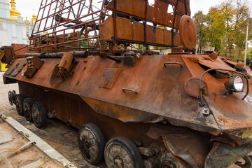 A destroyed rusty military vehicle stands outdoors on the street. Protection. Transport. Violence....
