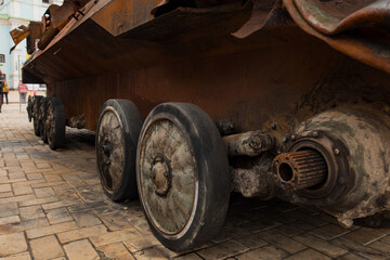 Fototapeta na wymiar The destroyed wheels of a rusty military vehicle stand outdoors on the street. Attack. Conflict. Destruction. Tank. Broken. Equipment. Rusty. Russia. Russian. Battle. Damage. Fight. Heavy. Defense