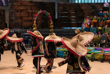 Day of the dead dancers with masks, caretas, dancing in front of an altar with skulls and flowers
