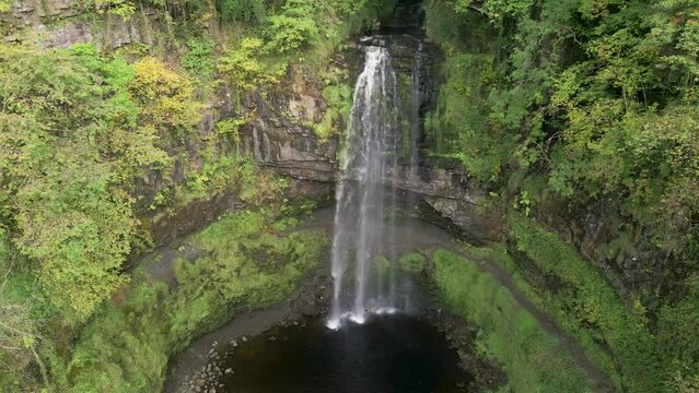 Aerial drone view descending down a spectacular waterfall (Henrhyd Falls)