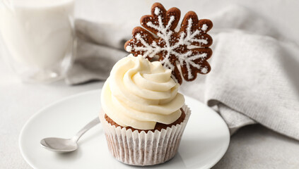 Plate with tasty Christmas cupcake on light background