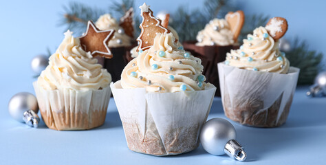 Delicious Christmas cupcakes on light blue background
