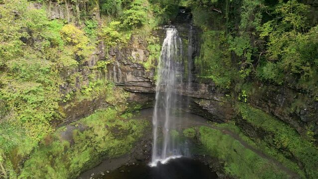 Panning camera view of a spectacular waterfall in a lush green forest