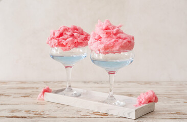 Glasses with delicious cotton candy cocktail on light wooden table - obrazy, fototapety, plakaty