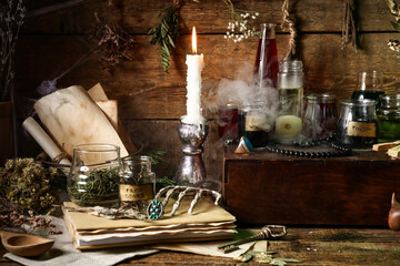 Jars with different potions, burning candle and fume on wooden background