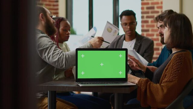 Diverse team of people working with greenscreen on laptop in business office. Coworkers using documents and isolated chroma key background, mockup copyspace and blank display template. Close up.