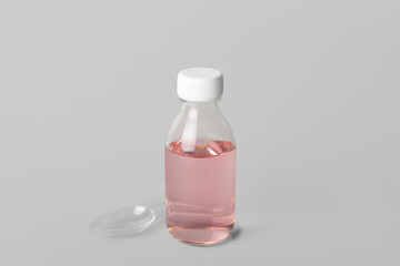 Bottle of cough syrup and spoon on grey background