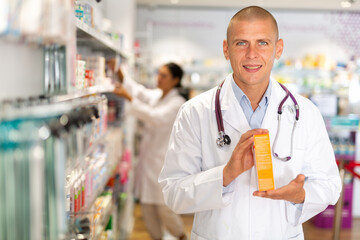 Male pharmacist offers medicine while standing in the trading floor of a pharmacy