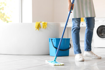 Young housewife mopping floor in bathroom