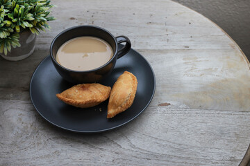 Curry puff and a cup of coffee on the wooden table 