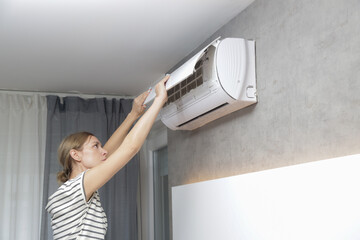 Woman repairing air conditioner at home.