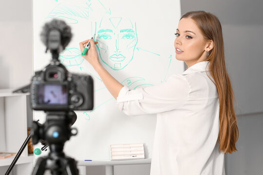 Young beauty blogger drawing on flipboard while recording video at home