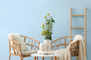 Interior of stylish living room with ikebana, table and armchairs