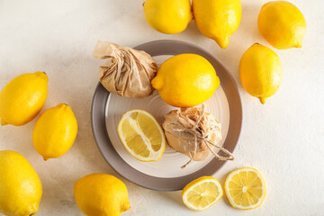 Plate with fresh lemons on light background