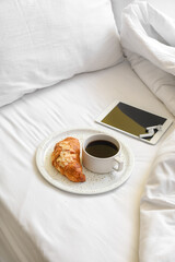 Plate with tasty breakfast, tablet computer and earphones on bed