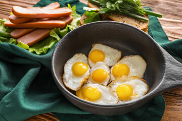 Frying pan with fried quail eggs on wooden table, closeup