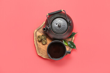 Board with cup of puer tea and teapot on red background