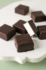 Wooden board with tasty bird's milk candies, closeup