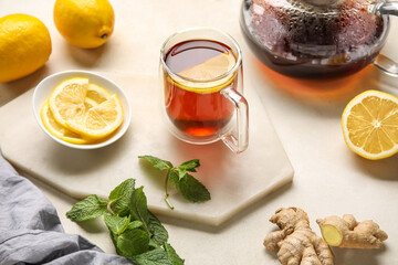 Board with glass cup of black tea, lemon and mint on white background