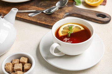 Cup of black tea with lemon and mint on white table, closeup