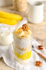 Glass jar of tasty chia seed pudding with banana on light table