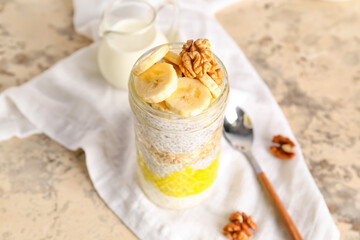 Glass jar of tasty chia seed pudding with banana on light table