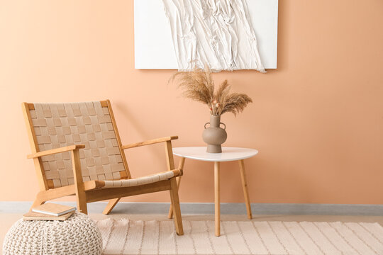 Interior of stylish living room with armchair, table and 3D textile artwork